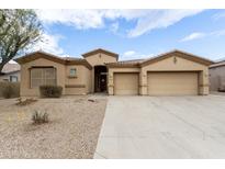 Charming home featuring a large driveway, three-car garage, and a well maintained desert landscape at 9734 S 182Nd Dr, Goodyear, AZ 85338