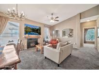 Inviting living room with a fireplace, antler chandelier, and gray carpet for a cozy atmosphere at 14250 W Wigwam Blvd # 1326, Litchfield Park, AZ 85340