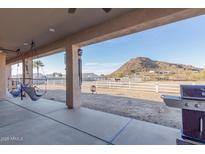 View of a covered patio with swing chairs, barbeque, white fencing and a distant mountain at 1444 W Gail Rd, San Tan Valley, AZ 85144