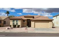 Charming single-story home featuring a well-manicured yard, a two-car garage, and a classic tile roof at 16132 W Ironwood St, Surprise, AZ 85374