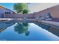 Backyard pool area featuring desert landscaping, a rock feature with palm tree reflections at 16132 W Ironwood St, Surprise, AZ 85374