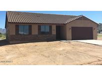 A charming single-story home featuring a two-car garage and low maintenance desert landscaping at 27411 N 256Th Dr, Wittmann, AZ 85361