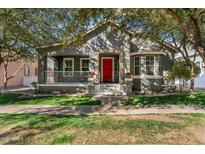 Charming home featuring a red front door, stone accents, covered porch, and lush green lawn at 3006 E Agritopia N Loop, Gilbert, AZ 85296