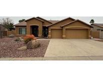 Charming home featuring a tile roof, desert landscaping, and a spacious three-car garage at 6881 W Greenbriar Dr, Glendale, AZ 85308