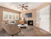 Inviting living room with a fireplace, ceiling fan, and bright windows with plantation shutters at 1295 N Ash St # 125, Gilbert, AZ 85233