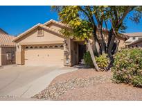 Single-story home featuring a well-kept lawn, a two-car garage, and a charming front porch with beautiful desert landscaping at 6334 W Desert Hollow Dr, Phoenix, AZ 85083