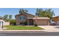 Charming two-story home with landscaped yard, desert plants, and an American flag above the garage at 1213 N Raven --, Mesa, AZ 85207