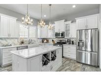 Bright kitchen with white cabinets, marble countertops, stainless steel appliances, and chandeliers at 14442 N Prickly Pear Ct, Fountain Hills, AZ 85268