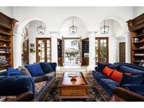 Elegant living room with white arches, dark wood shelving, and blue couches leading to a bright outdoor space at 6221 E Vista Dr, Paradise Valley, AZ 85253