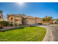 Beautiful single-story home with lush green lawn and a three car garage at 9617 E Holiday Way, Sun Lakes, AZ 85248