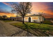 Cozy single-story home with neat front yard and sidewalk, highlighted by a dramatic sky at sunset at 10324 N 97Th Dr # B, Peoria, AZ 85345