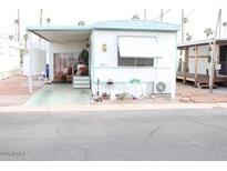 Charming mobile home featuring a covered parking area and a cozy front porch at 7807 E Main St # F-30, Mesa, AZ 85207