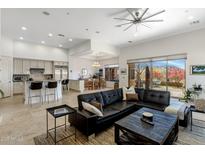 Bright and airy living room featuring a large sectional sofa, tile flooring, and seamless flow to the kitchen and dining areas at 10883 E La Junta Rd, Scottsdale, AZ 85255