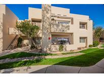 Beige two-story condo with well-manicured lawn, open balcony, and staircase on a sunny day at 11333 N 92Nd St # 2028, Scottsdale, AZ 85260