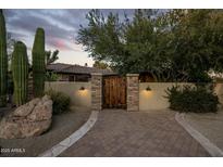 Inviting desert home with a lighted courtyard entry featuring a custom wood gate and beautiful desert landscaping at 11021 N 74Th St, Scottsdale, AZ 85260