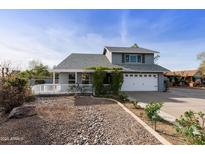 Charming gray two-story home featuring a well-manicured front yard and a cozy covered porch at 1655 W Meseto Cir, Mesa, AZ 85202