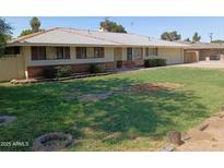Charming single-level home featuring a manicured lawn, brick accents, and attached two car garage at 4909 E Osborn Rd, Phoenix, AZ 85018
