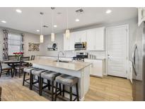 Modern kitchen with white cabinets, stainless steel appliances, a kitchen island, and counter seating at 9923 E Texas Ave, Mesa, AZ 85212