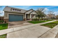Inviting single-Gathering home features a brick driveway, blue garage door, and meticulously maintained front yard at 3485 E Silo Dr, Gilbert, AZ 85296