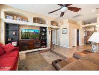 Spacious living room with built-in shelving, a ceiling fan, and comfortable seating area at 5932 W Poinsettia Dr, Glendale, AZ 85304