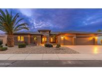 Inviting home exterior featuring a well-manicured yard, rock landscaping, and a three-car garage at 15558 W Big Sky Dr, Surprise, AZ 85374
