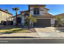 Charming two-story home featuring a two-car garage, tiled roof, palm trees, and manicured landscaping at 17311 N Kimberly Way, Surprise, AZ 85374