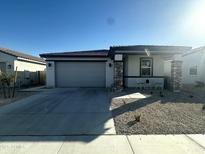 Charming single-story home featuring a two-car garage, desert landscaping, and covered porch with stone accents at 18231 W Paraiso Dr, Surprise, AZ 85387