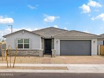 Charming single-story home with a gray exterior, a gray tiled roof, and a brick driveway at 4029 S 176Th Dr, Goodyear, AZ 85338