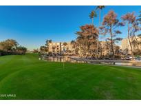 Scenic view of lush green golf course with a pond and building in the background under a clear blue sky at 7920 E Camelback Rd # 408, Scottsdale, AZ 85251