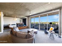 Bright living area featuring concrete ceilings, a modern sofa and sliding glass doors to a patio with city views at 6850 E Main St # 4404, Scottsdale, AZ 85251