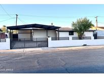 Charming single-story home featuring a covered carport and modern horizontal slat privacy fence at 7754 W Mitchell Dr, Phoenix, AZ 85033