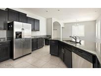 A spacious kitchen featuring dark cabinetry, stainless steel appliances, and a granite countertop island with a sink at 1170 E Taylor Trl, San Tan Valley, AZ 85143