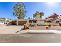 Inviting single-story home with a desert landscape and a two-car garage at 2407 W Paradise Ln, Phoenix, AZ 85023