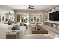 Staged living room featuring a ceiling fan, built-in shelving, and sliding glass doors to the backyard at 26635 W Covey Ln, Buckeye, AZ 85396