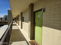 Hallway view featuring a light green door with the unit number E-402 on the door with a neutral colored rug in front of the door at 349 E Thomas Rd # E402, Phoenix, AZ 85012