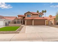 Two-story home featuring a red tile roof, desert landscaping, and an attached three-car garage at 4129 E Nighthawk Way, Phoenix, AZ 85048