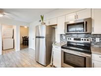 Modern kitchen with a stainless steel refrigerator, microwave, range, and access to the dining area at 10909 W Santa Fe Dr, Sun City, AZ 85351