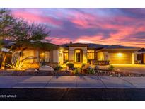 Inviting single-story home with desert landscaping, warm exterior lighting, and a colorful sunset sky at 2415 W Hazelhurst Ct, Anthem, AZ 85086