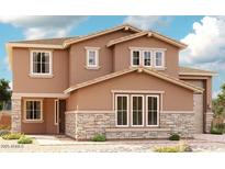 Charming two-story home with tan stucco, stone accents, a well-manicured lawn and blue skies at 21750 E Saddle Way, Queen Creek, AZ 85142