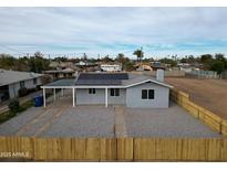 Single story home with gravel yard, solar panels, and a light-colored fence at 318 E Hill Dr, Avondale, AZ 85323