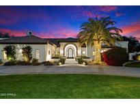 Stunning home exterior at dusk with a well-manicured lawn, inviting entrance and a lovely illuminated palm tree at 13670 N 85Th Pl, Scottsdale, AZ 85260