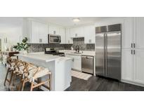 Bright kitchen features white cabinets, stainless steel appliances, and stylish herringbone backsplash at 4950 N Miller Rd # 119, Scottsdale, AZ 85251