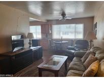 Cozy living room featuring a comfortable sofa, ceiling fan, and large windows for natural light at 8211 E Garfield St # J206, Scottsdale, AZ 85257