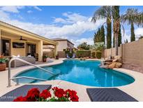 Inviting backyard pool with rock waterfall feature, lush landscaping, and comfortable lounge area for relaxation and enjoyment at 21842 E Via De Olivos --, Queen Creek, AZ 85142