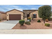 Charming tan home with a well-manicured desert-landscaped front yard and a brown two-car garage door at 41737 W Cribbage Rd, Maricopa, AZ 85138