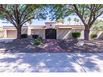 Charming home with a decorative iron gate, brick walkway, and manicured landscaping at 9740 E Gold Dust Ave, Scottsdale, AZ 85258