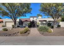 Charming single-story home featuring an ornate front gate and landscaped front yard with desert plants and trees at 9740 E Gold Dust Ave, Scottsdale, AZ 85258