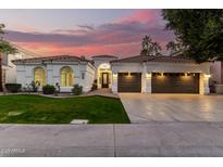 Beautiful home exterior with arched windows, tile roof, lush landscaping, and multi-car garage at sunset at 2043 E Clipper Ln, Gilbert, AZ 85234