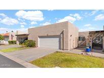 Neutral-toned home with a two-car garage, green lawn, desert landscaping, and tile roof at 3345 E University E Dr # 71, Mesa, AZ 85213