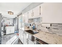 Bright kitchen showcasing white cabinets, granite countertops, and a stainless steel sink at 10533 W Granada Dr, Sun City, AZ 85373